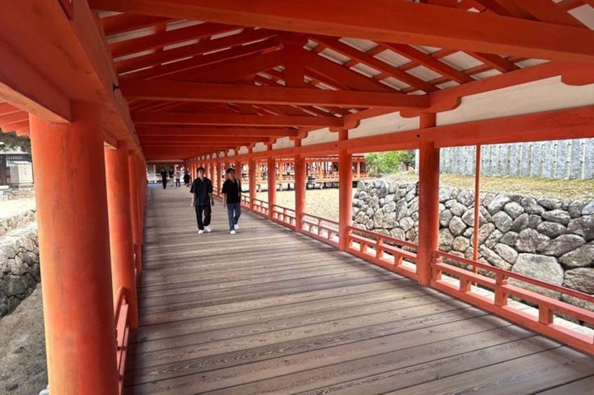 En träpromenad med röda pelare som leder fram till en stenmur. 4
