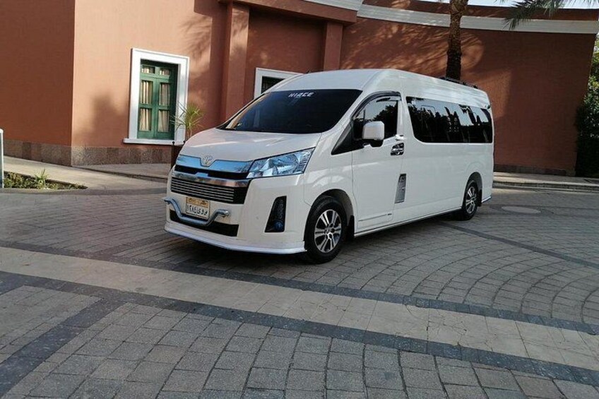 Una camioneta blanca estacionada en un área pavimentada, con un edificio al fondo. 5