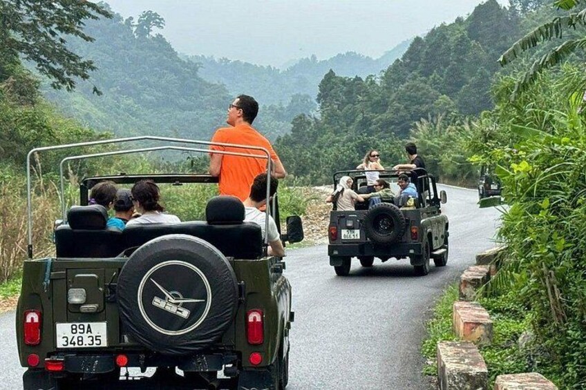 Two off-road vehicles on a narrow road surrounded by lush greenery. 3