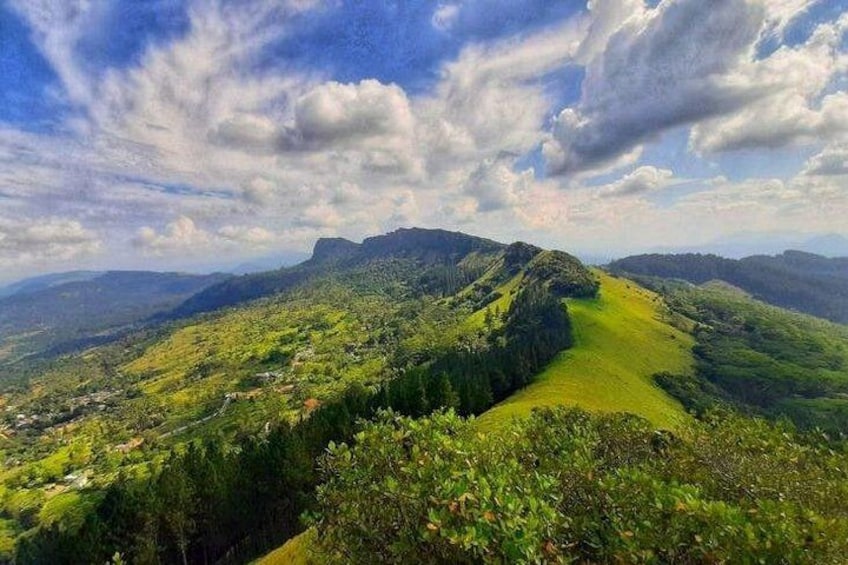 A mountainous landscape with a valley, a winding path, and a distant town. 3