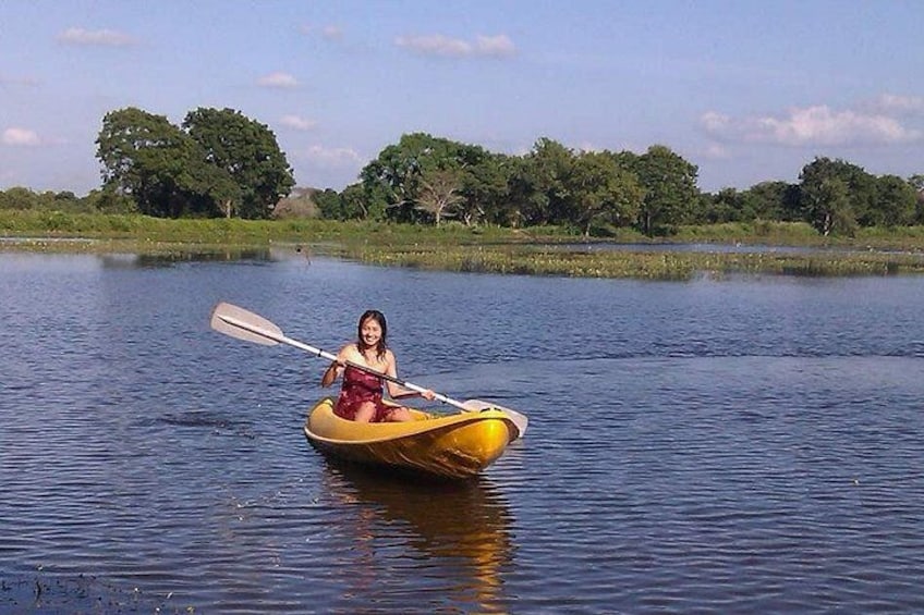 A person in a yellow kayak on a calm body of water with trees in the background. 5