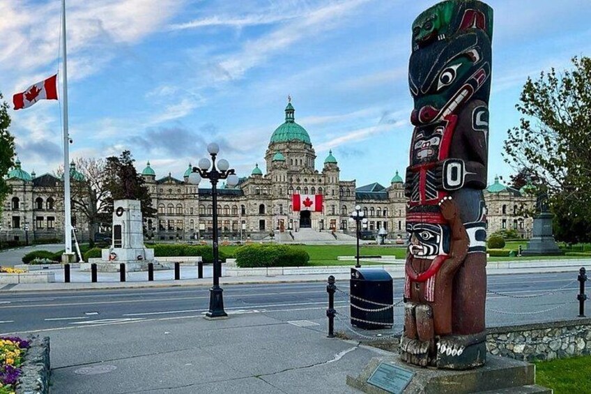 Un totem, un drapeau canadien et un bâtiment gouvernemental surmonté d’un dôme vert. 1