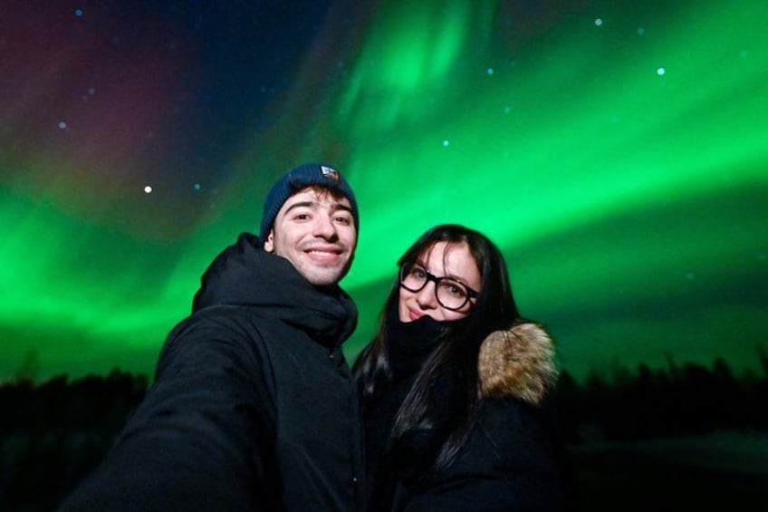 To personer tager en selfie med nordlys på baggrunden. 2