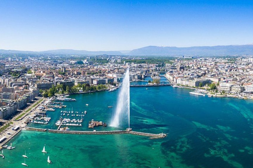Una città costiera con una fontana imponente, acque blu cristalline e un porto turistico con barche. 2