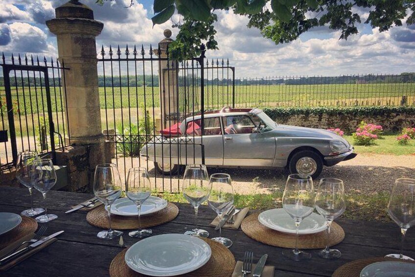 A table set for a meal with a vintage car parked in the background. 1