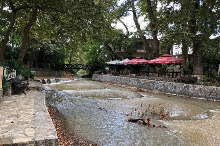 Un sentiero in pietra accanto a un canale d'acqua, alberi e ombrelloni rossi. 3