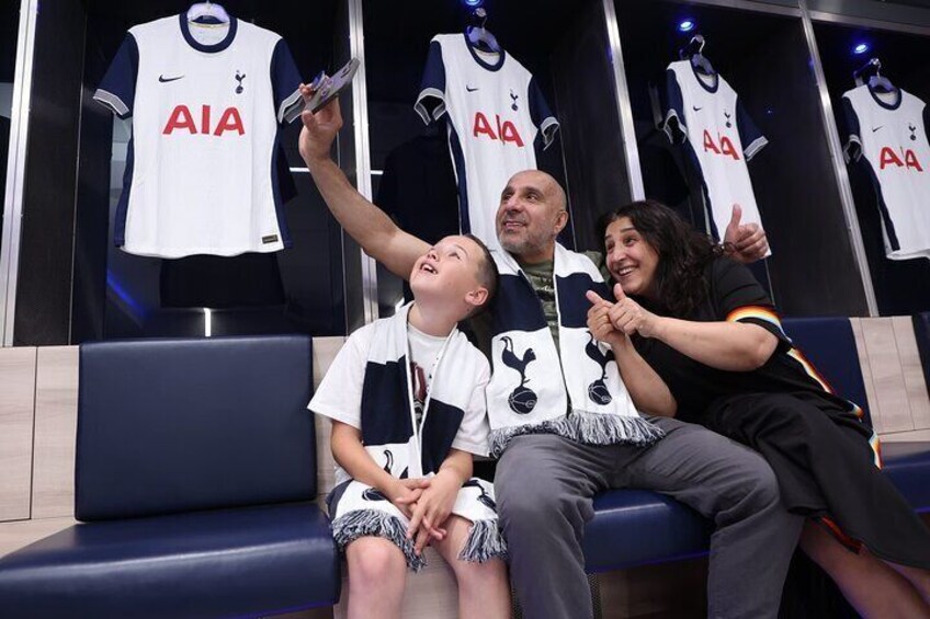 A family sitting on a bench in a sports lounge, looking at a display of white sports jerseys with 'AIA' written on them. 5