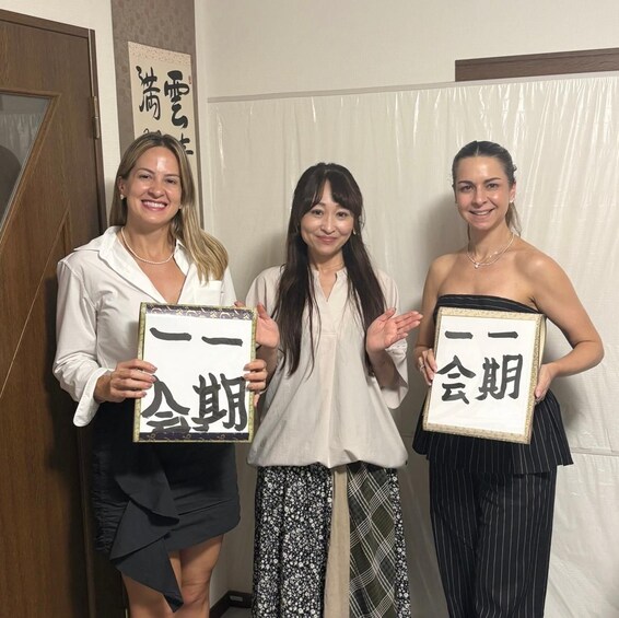 Three individuals holding framed signs with Japanese characters. 2