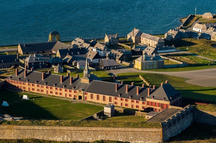 En kuststad med historiska byggnader, en framträdande röd byggnad och en befäst mur. 1