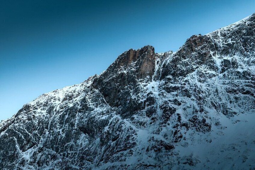 A snow-covered mountain peak with sharp ridges and a clear blue sky. 2
