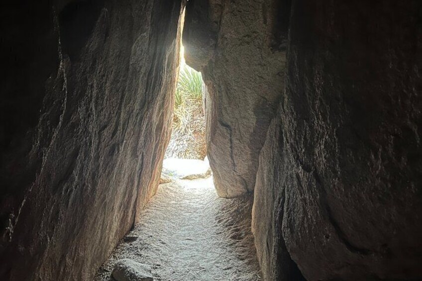 A narrow passageway between large rock formations with sunlight filtering through. 4
