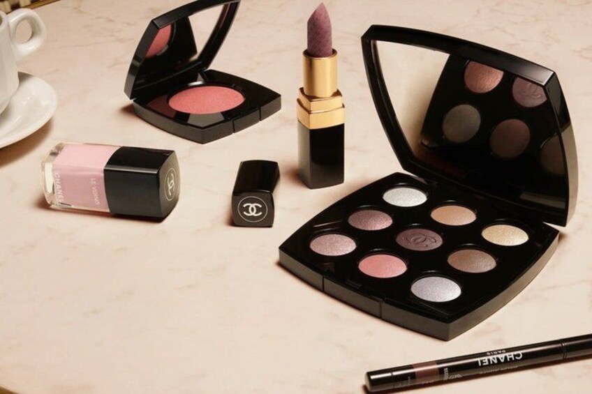Une palette de maquillage, un rouge à lèvres et un flacon de vernis à ongles, le tout posé sur une surface en marbre. 4