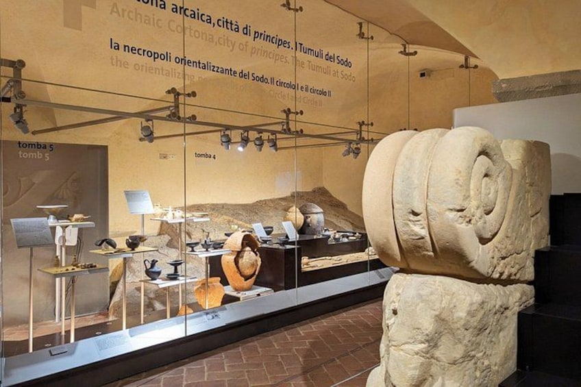 En arkeologisk utställning med artefakter, inklusive en stor stenskulptur och informativa utställningstavlor. 3