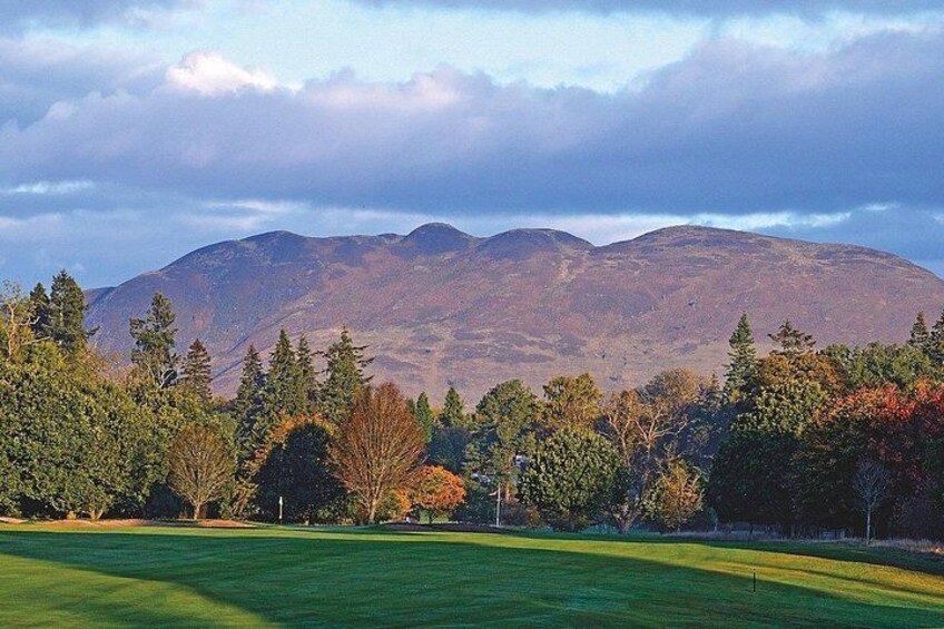 Un campo de golf con una cadena montañosa al fondo. 4