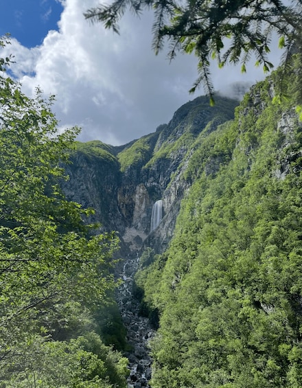 A lush green valley with a waterfall cascading down a rocky cliff. 2