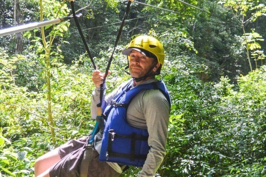 Una persona deslizándose en tirolesa por un bosque frondoso. 2