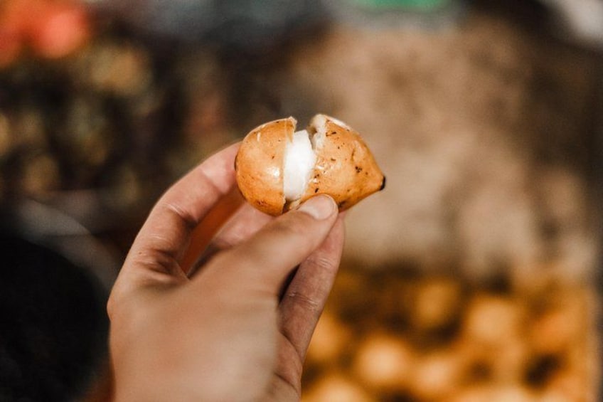A hand holding a half-eaten pastry with a white filling. 1
