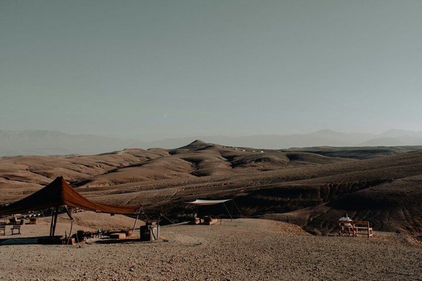 A desert landscape with rolling hills, a tent, and a small table. 4
