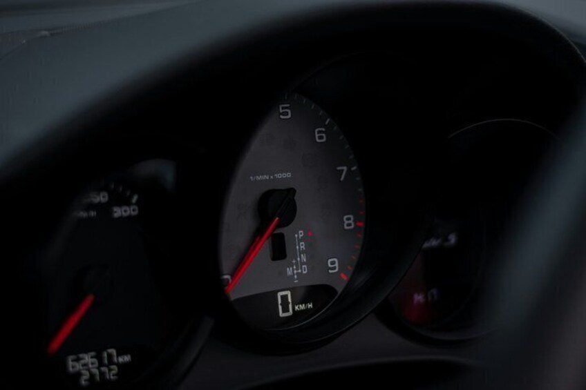 A car's speedometer and tachometer with a red needle. 4