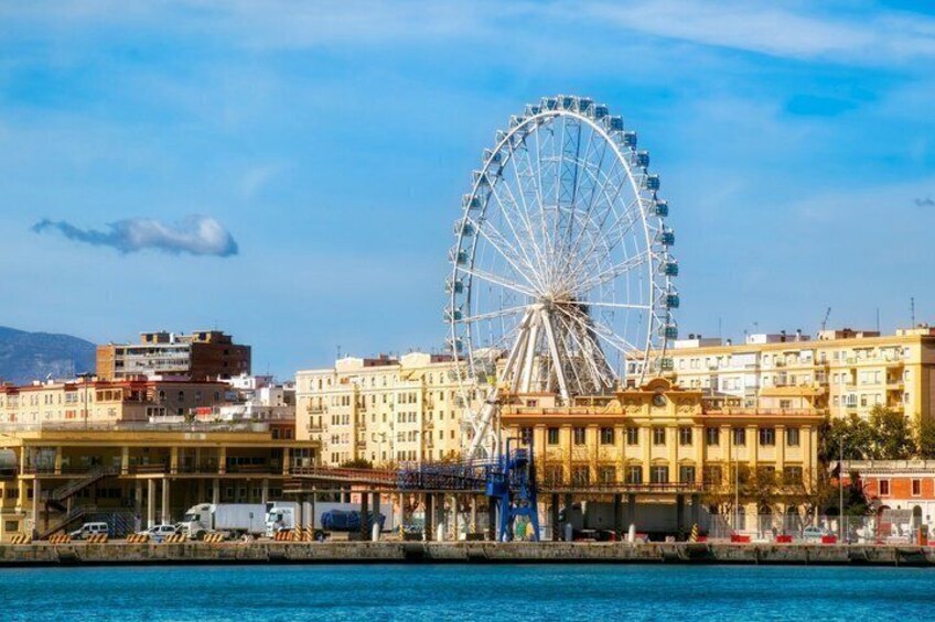 Un paisaje urbano frente al agua, con una noria destacada y varios edificios. 2