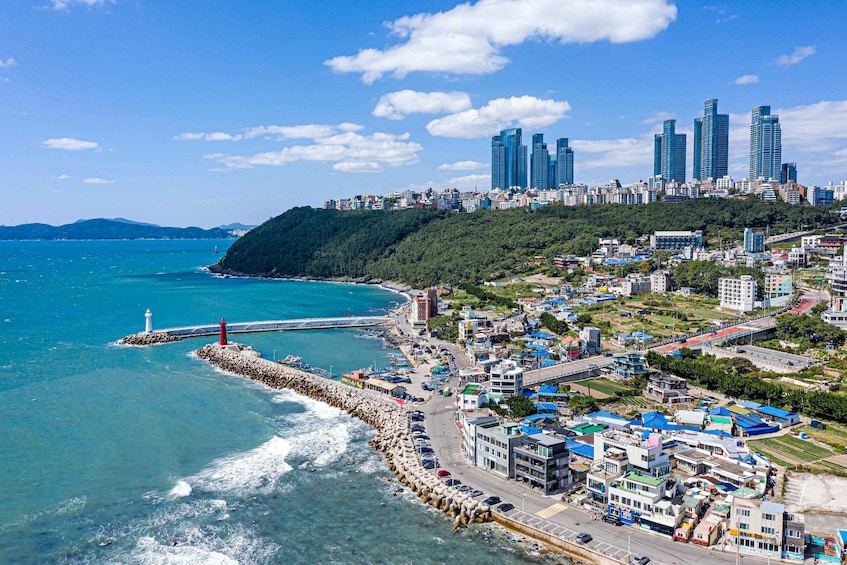 A coastal cityscape with a lighthouse, a breakwater, and high-rise buildings. 1
