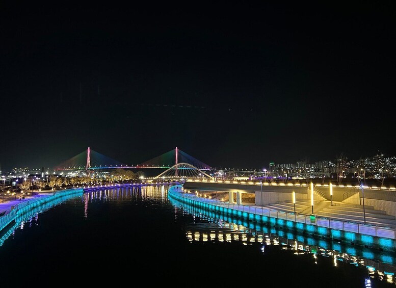 A nighttime view of a brightly lit bridge with a cityscape in the background. 3