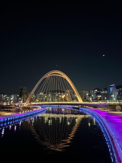 A brightly lit bridge with a reflection in the water below. 4