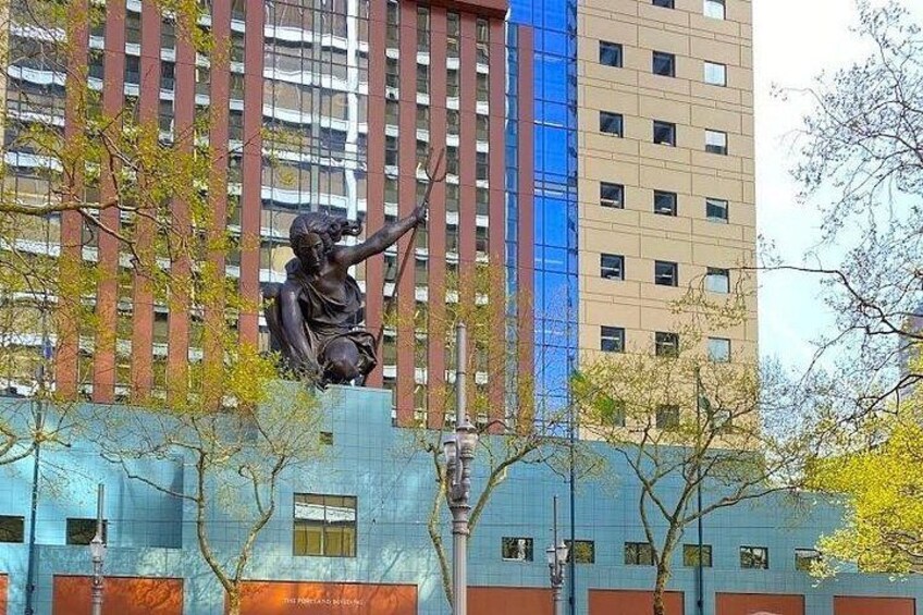 A statue of a figure with raised arms, a building with vertical lines, and trees with sparse leaves. 2