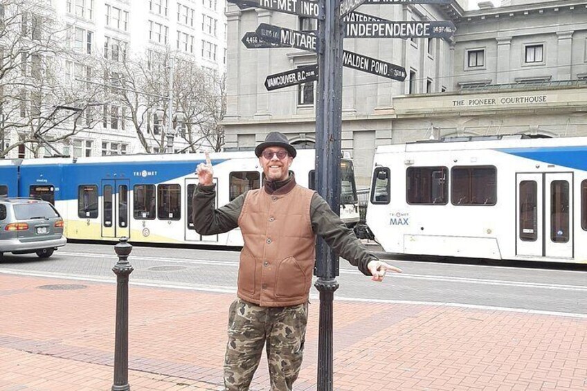 A man standing on a sidewalk with a train in the background. 3