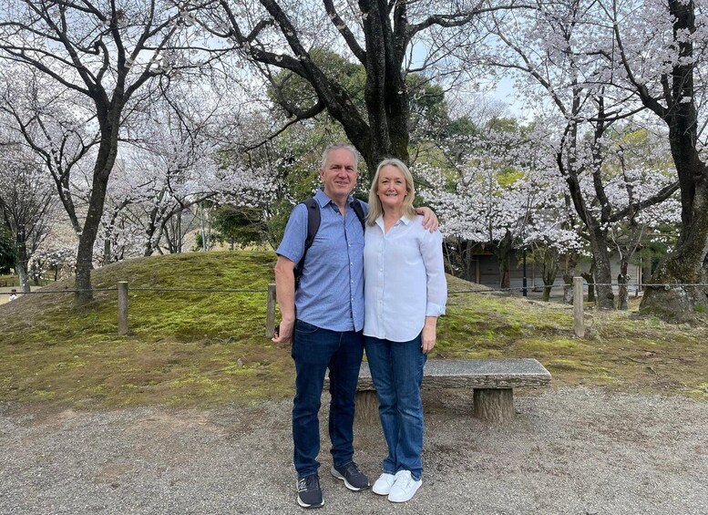 Two people standing in a park with cherry blossoms. 3