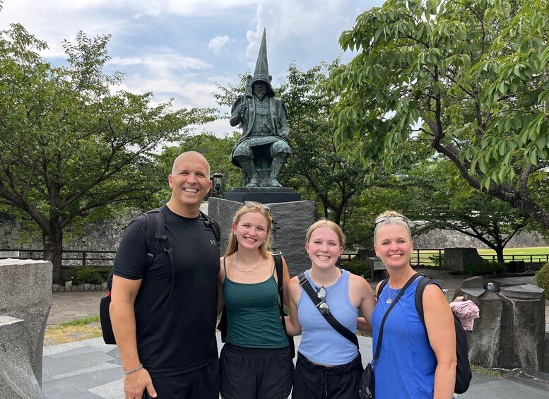 A group of people standing in front of a statue with a pointed hat and a staff. 5