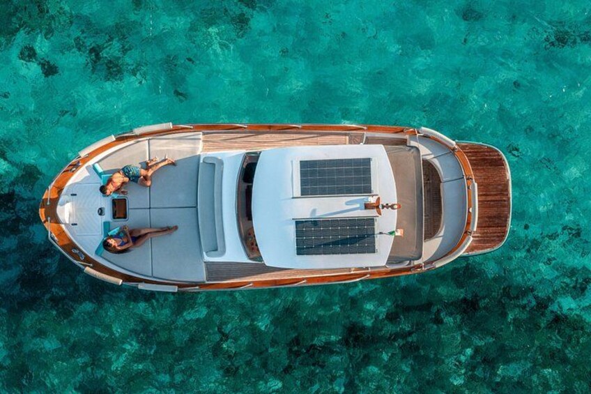 Un bateau avec deux personnes à bord, un panneau solaire et une eau turquoise cristalline. 4