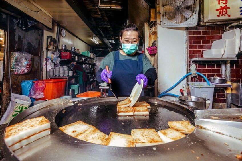 Une personne est en train de cuisiner sur une grande plaque de cuisson, avec plusieurs aliments. 3