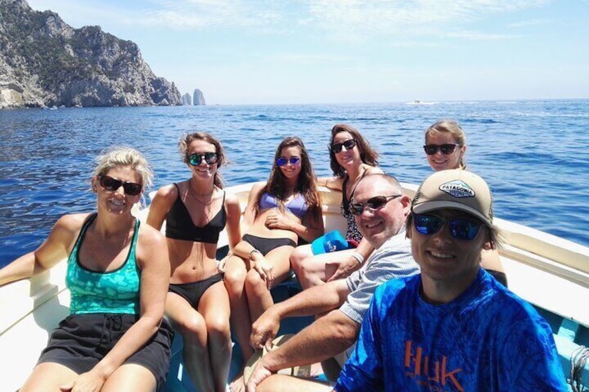 A group of people on a boat in the ocean with rocky cliffs in the background. 2