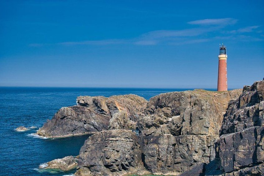 A lighthouse on a rocky coastline with the ocean in the background. 4