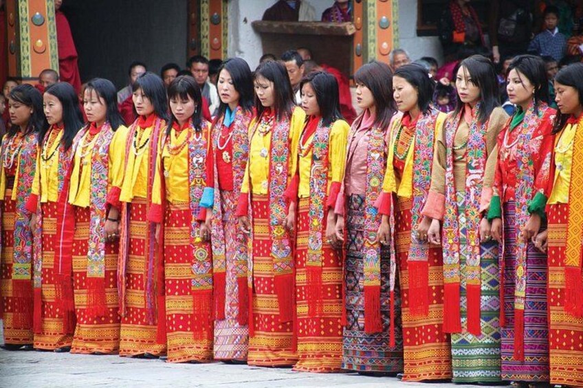 A group of women in traditional colorful attire standing in a line. 5
