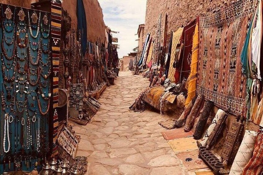 A narrow street lined with shops selling jewelry and textiles. 2