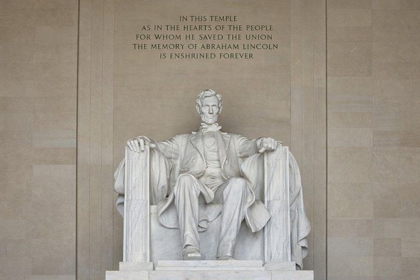 A marble statue of Abraham Lincoln seated on a pedestal with a plaque. 5