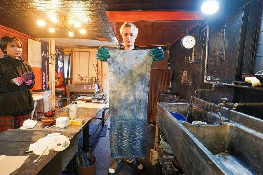 A person holding a large blue and white patterned fabric in a kitchen setting with various cooking utensils and a sink. 4