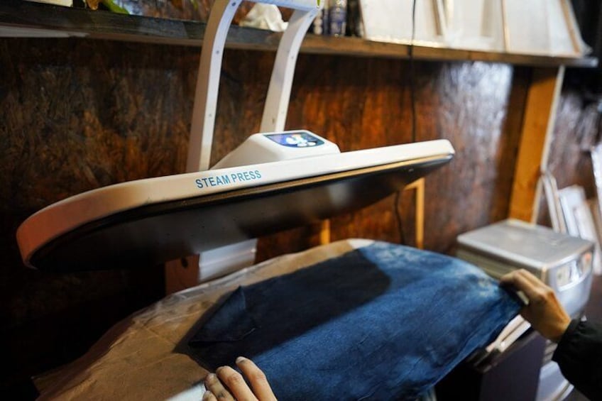 A person using a steam press on denim fabric. 3