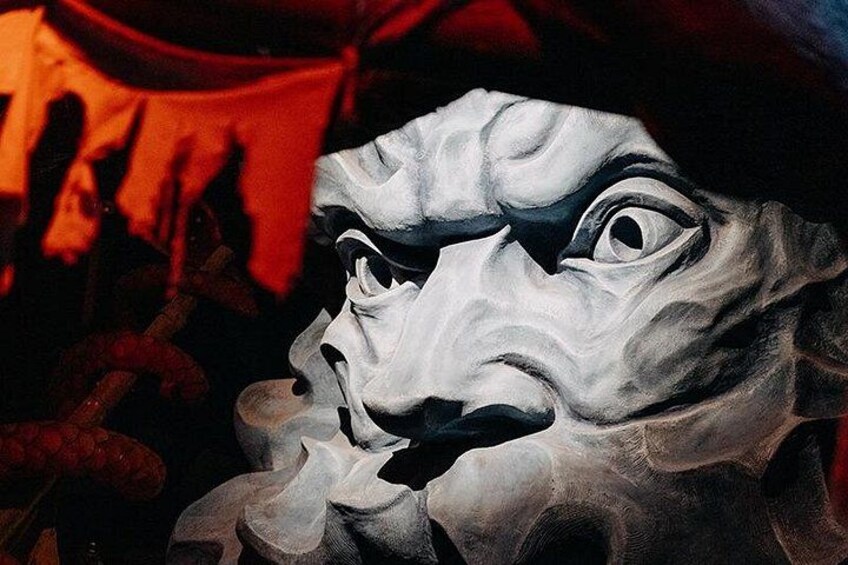 A sculpture with a human-like face, possibly a mask, with a dramatic expression. 2
