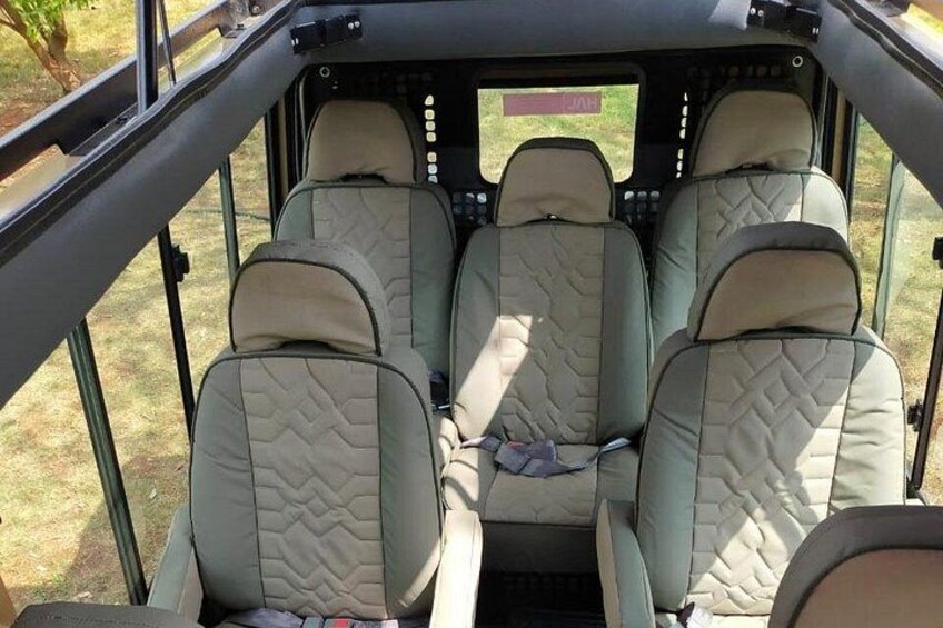 A vehicle interior with four beige seats and a steering wheel. 3
