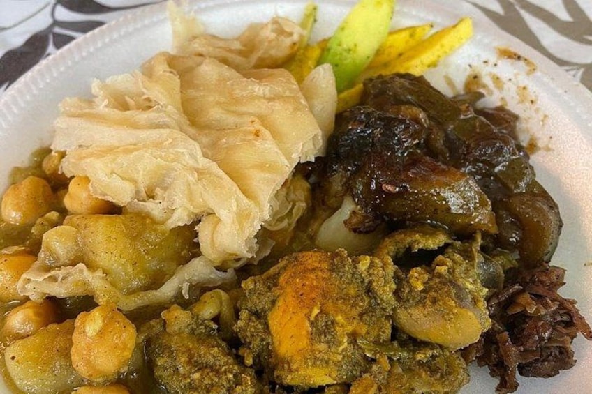A plate of food with various dishes including what appears to be chicken, chickpeas, and a green sauce. 4