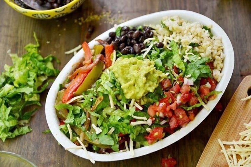 A bowl of salad with various ingredients like lettuce, tomatoes, black beans, and avocado. 1