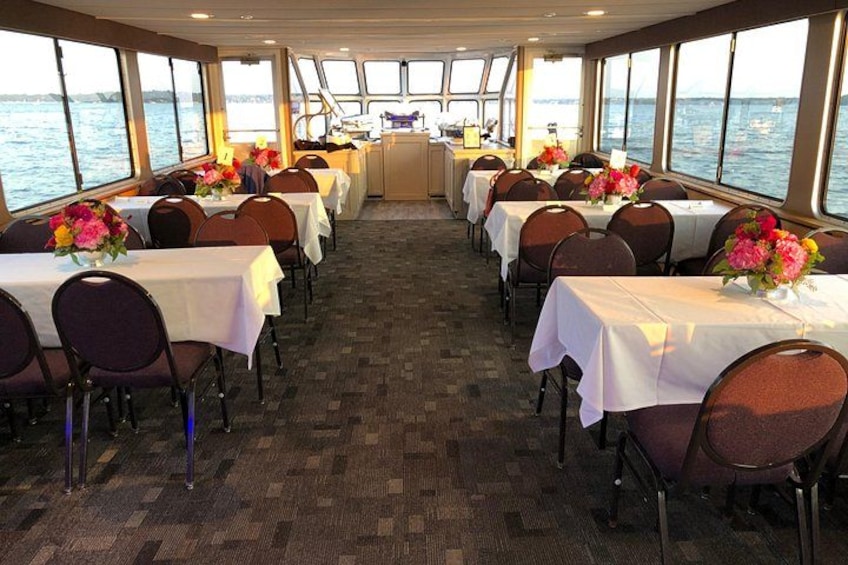 A dining area with tables and chairs, large windows, and a view of the sea. 2