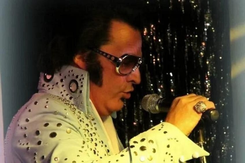 A person wearing a white outfit with circular patterns, holding a microphone. 4