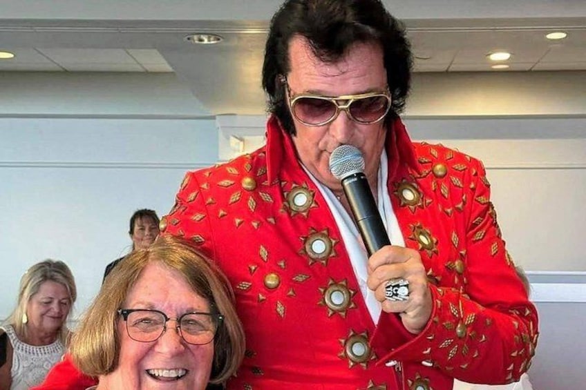 A person in a red jacket with gold embellishments holding a microphone. 1