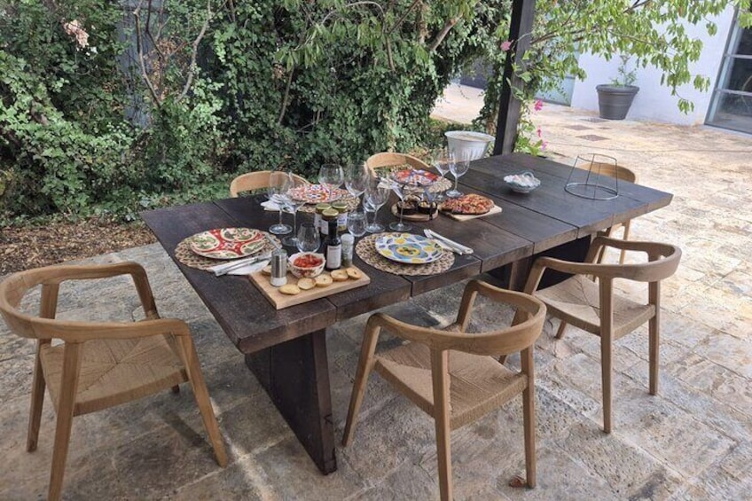 Mesa de madera al aire libre con platos, vasos y comida. 4