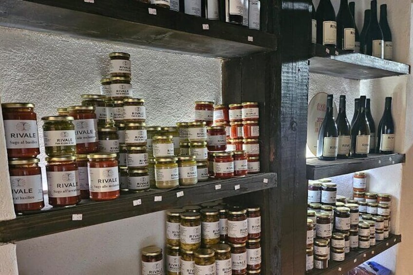 Estantes llenos de frascos de conservas RIVALE y botellas de vino. 3