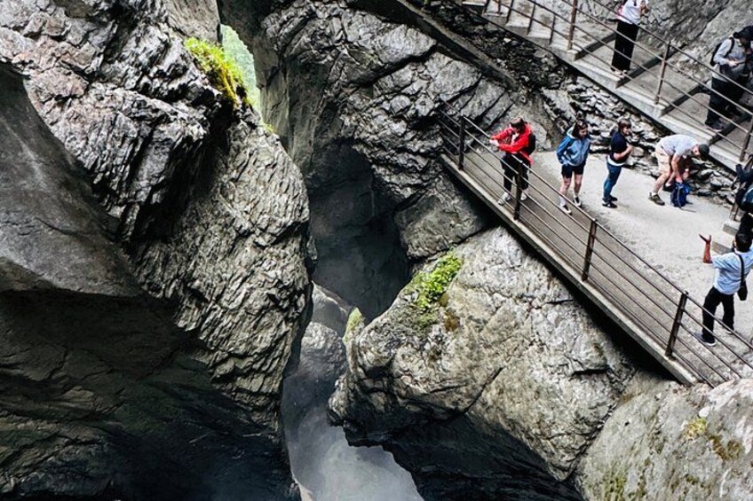 Un cañón rocoso con un puente peatonal y gente caminando. 3